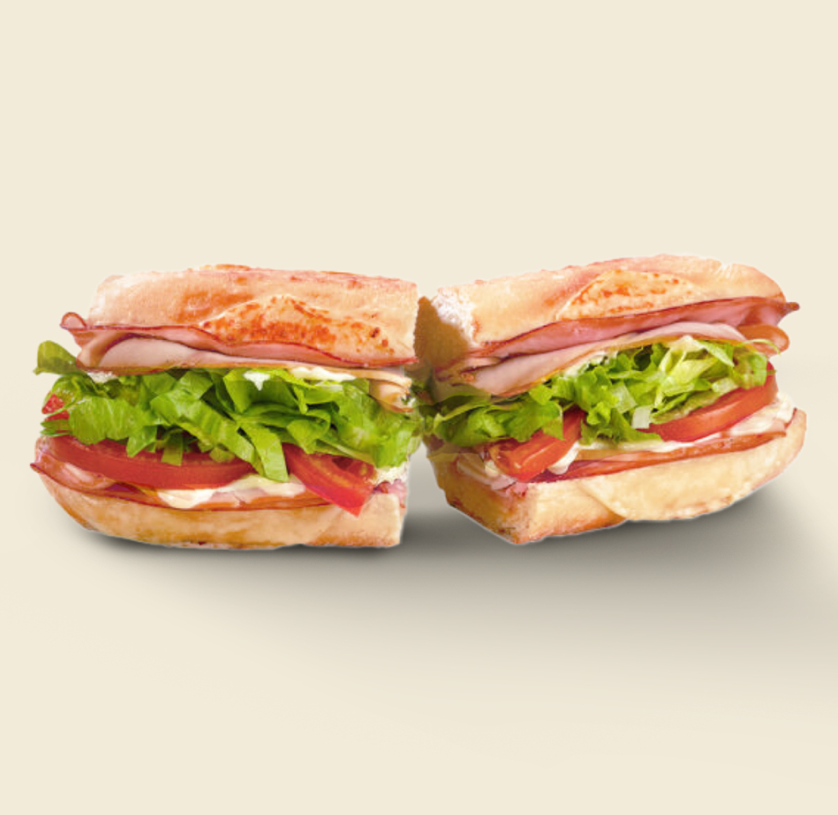 The Café Club Sandwich, layered with smoked ham, oven-roasted turkey, crispy bacon, lettuce, tomato, and creamy mayo on freshly baked artisan bread.